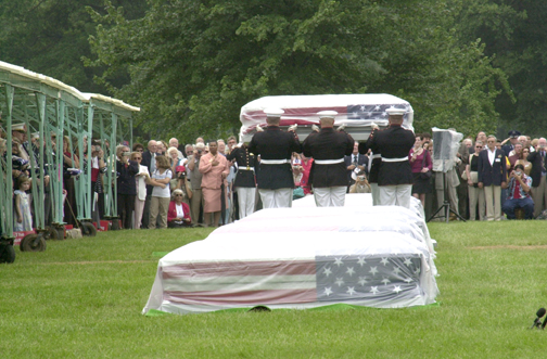 Body bearers from Marine Barracks 8th and I, Washington, D. C. raise the casket containing the group remains of the Makin Raiders above their heads before laying it to rest beside the other remains.
 Photo by: Sgt. M. V. Trindade